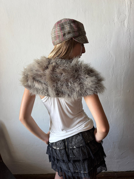 model wearing gray faux fur collar/boonie jacket over a white tank top and a black ruffled skirt, with CHECKERED CAP.