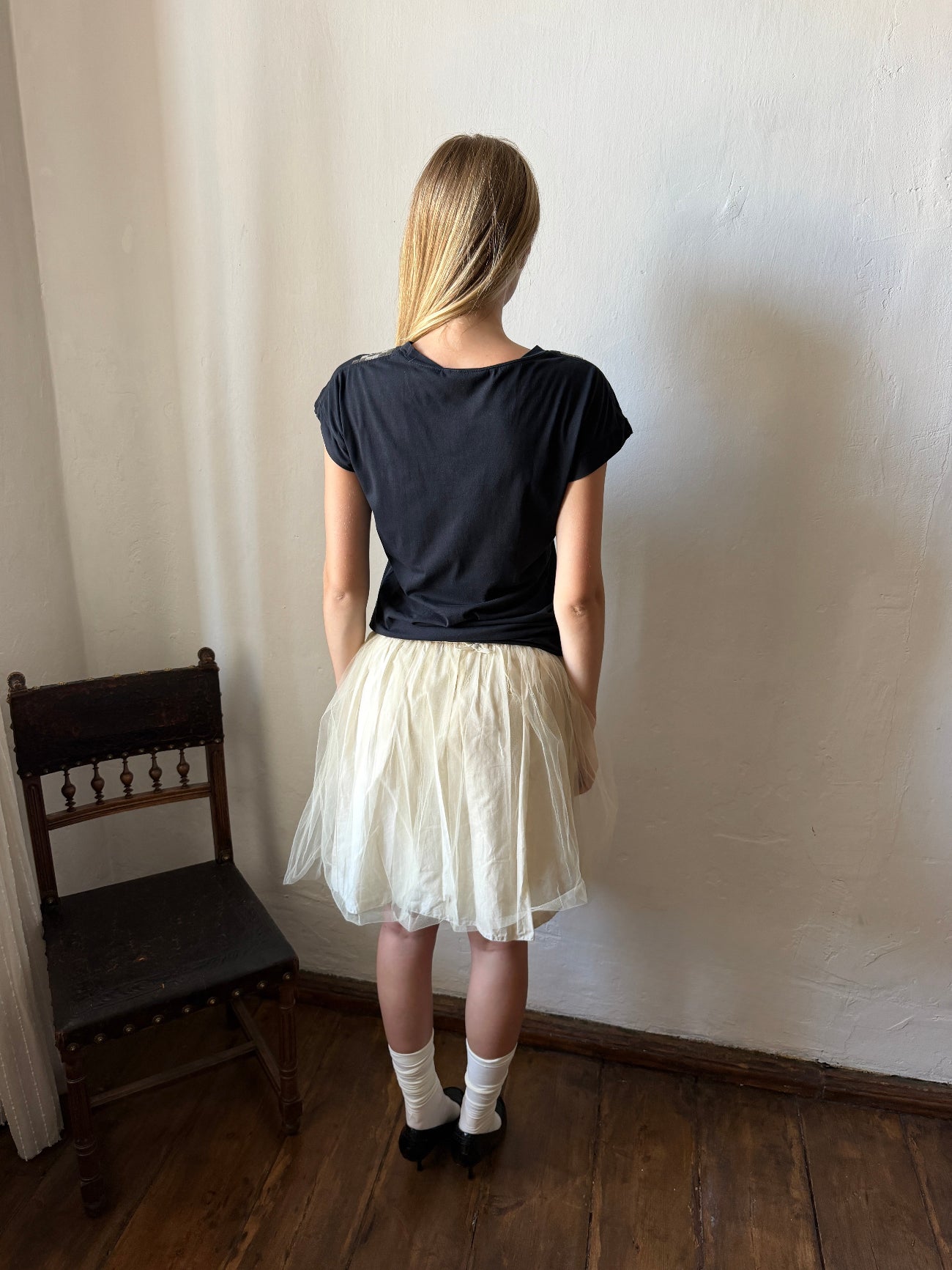 model wearing a black short-sleeve t-shirt and a voluminous cream tulle skirt